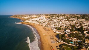 An aerial view of a coastal city with a beach, residential buildings, and a clear sky.