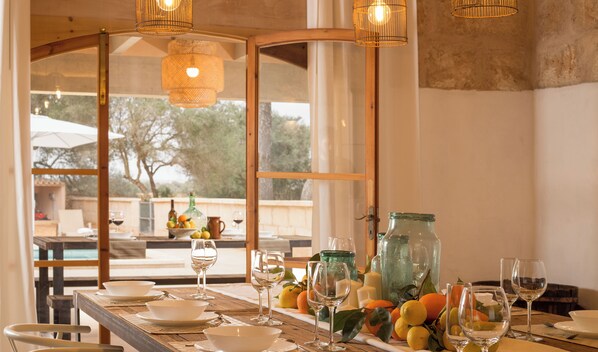 A dining table set with plates, glasses, and a fruit arrangement.