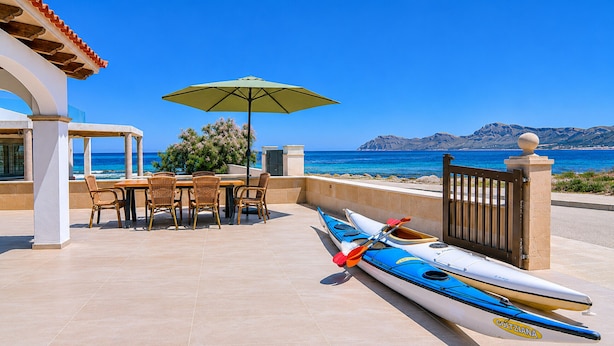 Eine Terrasse mit Tisch und Stühlen, einem Kajak und Blick auf das Meer.