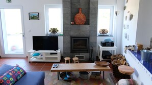 Ett vardagsrum med TV, öppen spis och en matplats.