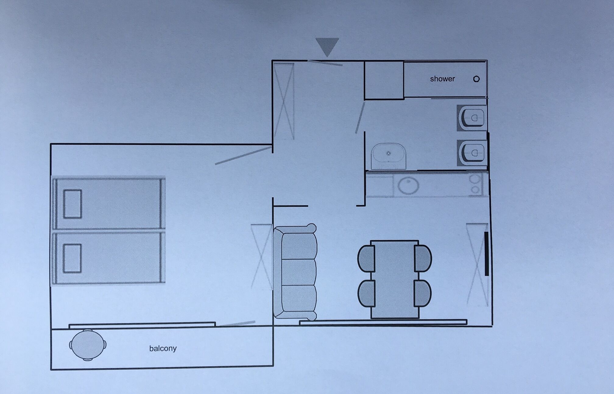 A floor plan of a hotel room with a balcony, a shower, a sink, and a dining area.