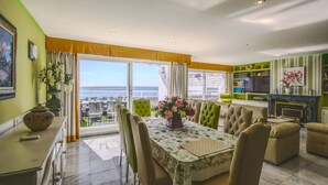 A dining area with a table set for four, a sofa, and a view of the sea. - 1149 Stunning Duplex Penthouse with Panoramic Sea Views (Marbella)
