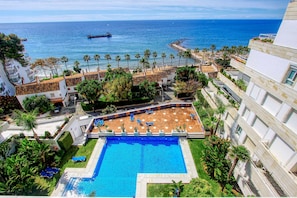 Un resort con piscina, palmeras y vista al océano.