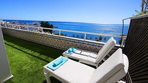 A balcony with white lounge chairs, a patterned wall, and a view of the ocean. - 1149 Stunning Duplex Penthouse with Panoramic Sea Views (Marbella)