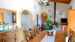 A dining area with a wooden table and chairs, a potted plant, and a television in the background. - Casa Inés 165 magnificent finca with private pool, large garden, air conditioning and WiFi (Son Serra de Marina)