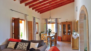 A cozy living room with a sofa, dining table, and wooden cabinets. - Casa Inés 165 magnificent finca with private pool, large garden, air conditioning and WiFi (Son Serra de Marina)