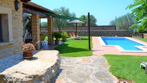 A stone patio leading to a swimming pool with a stone wall and a thatched umbrella. - Casa Inés 165 magnificent finca with private pool, large garden, air conditioning and WiFi (Son Serra de Marina)