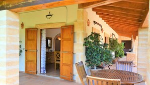 An open wooden door leading to a dining area with a table and chairs, surrounded by potted plants and a stone wall. - Casa Inés 165 magnificent finca with private pool, large garden, air conditioning and WiFi (Son Serra de Marina)