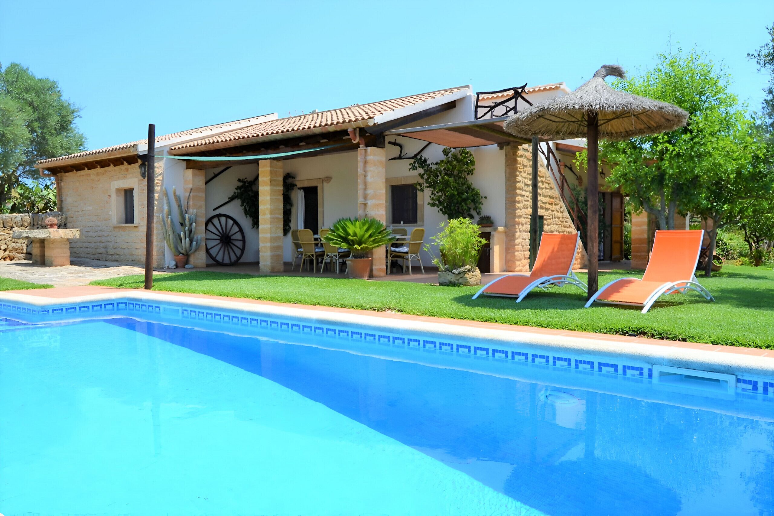 A poolside area with a pool, lounge chairs, and a covered patio.