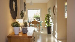Een hal met een houten bankje, planten in potten en wanddecoratie.