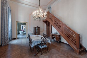A dining room with a wooden staircase, a chandelier, and a dining table set for four.