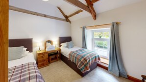 A bedroom with two beds, a wooden desk, and a window with curtains. - Family friendly coachhouse in idyllic setting with extensive private grounds and free WiFi (Swansea)