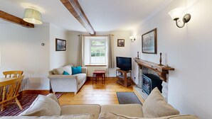 A cozy living room with a fireplace, a television, and a comfortable seating area. - Family friendly coachhouse in idyllic setting with extensive private grounds and free WiFi (Swansea)