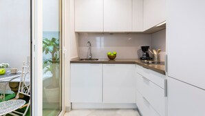 A modern kitchen with white cabinets, a stainless steel sink, and a bowl of apples on the counter. - Genteel Home Galera I (Sevilla)