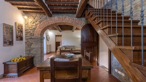 Ein rustikales Interieur mit einem Holzesstisch, einem Steingewölbe und einer Holztreppe.