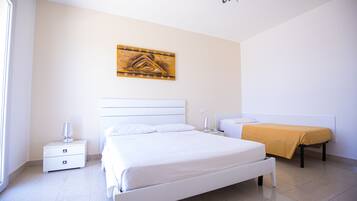 A modern bedroom with a large bed, bedside tables, a bedside lamp, and a wall-mounted artwork.