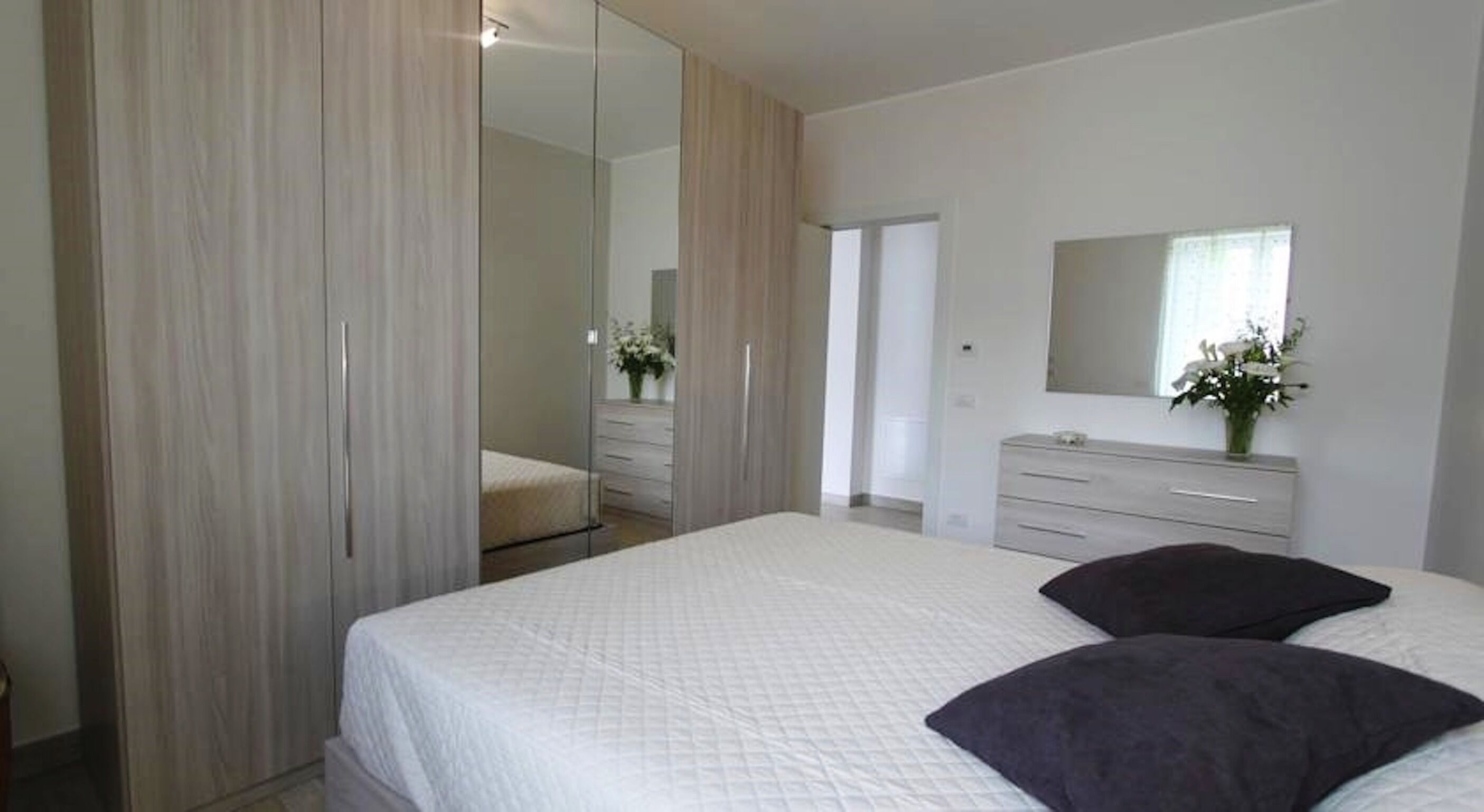 Une chambre à coucher avec un grand lit, une armoire, une commode et un miroir.
