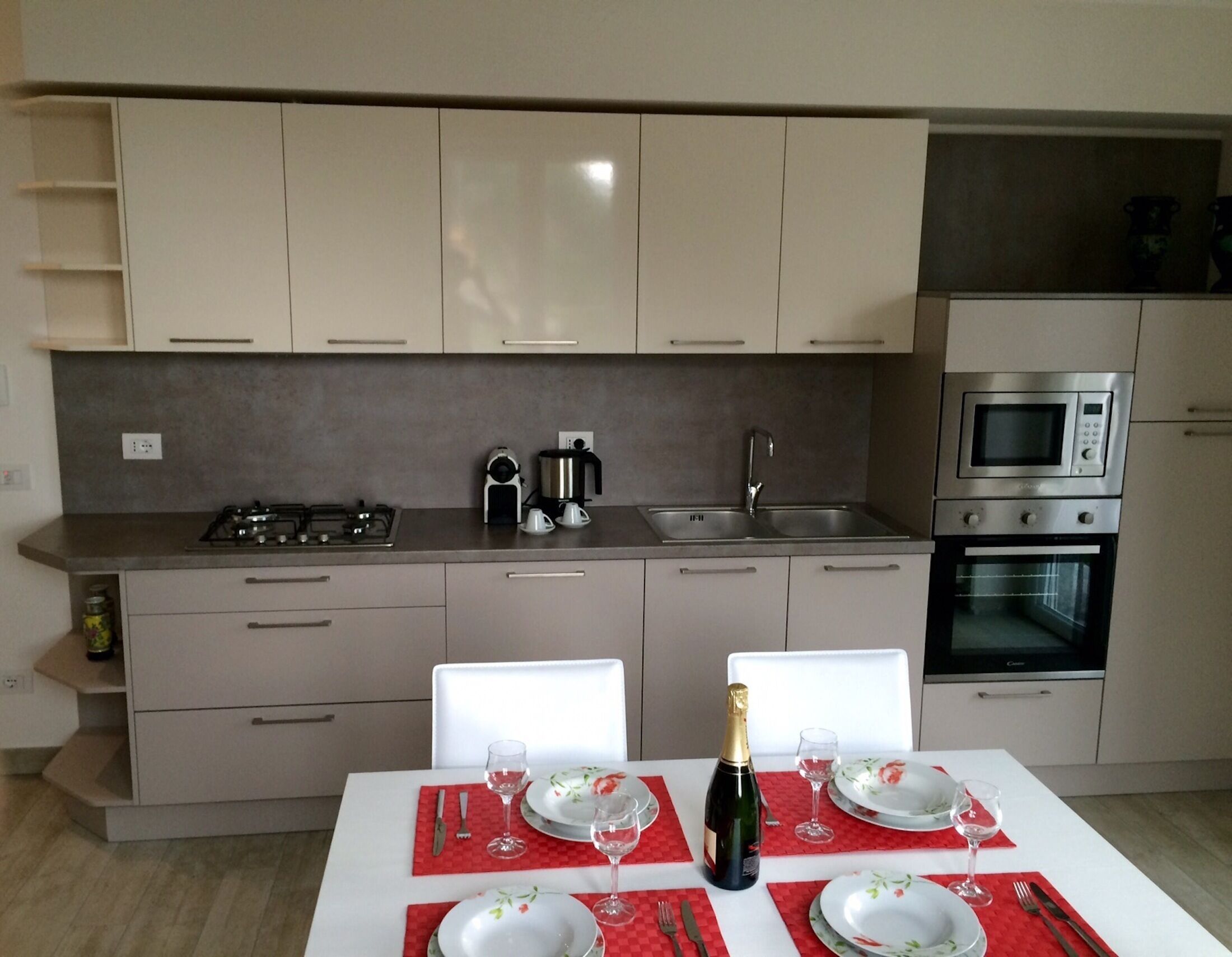 A modern kitchen with a dining table set for two, a coffee maker, and a microwave.
