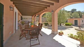 An outdoor patio with a wooden table and chairs, surrounded by arches and potted plants. - Victori - Charming country house with pool in Sineu, Mallorca (Sineu)