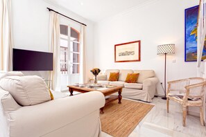 A living room with a sofa, a coffee table, a TV, a lamp, and a chair.