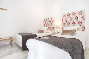 A double room with two beds, a bedside table, a nightstand, and a wall-mounted lamp.