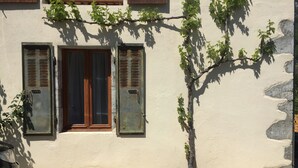 Un bâtiment à la façade beige, avec une porte en bois et deux fenêtres dotées de volets.