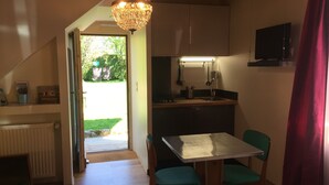 Une cuisine compacte avec un coin repas, un radiateur et un téléviseur fixé au mur.