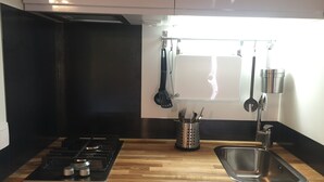 Une cuisine moderne dotée d’un plan de travail en bois, d’un évier en acier inoxydable et d’une cuisinière à gaz.