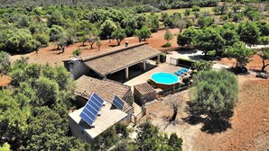 Une villa dotée d’une piscine, de panneaux solaires et d’un patio entouré d’arbres.