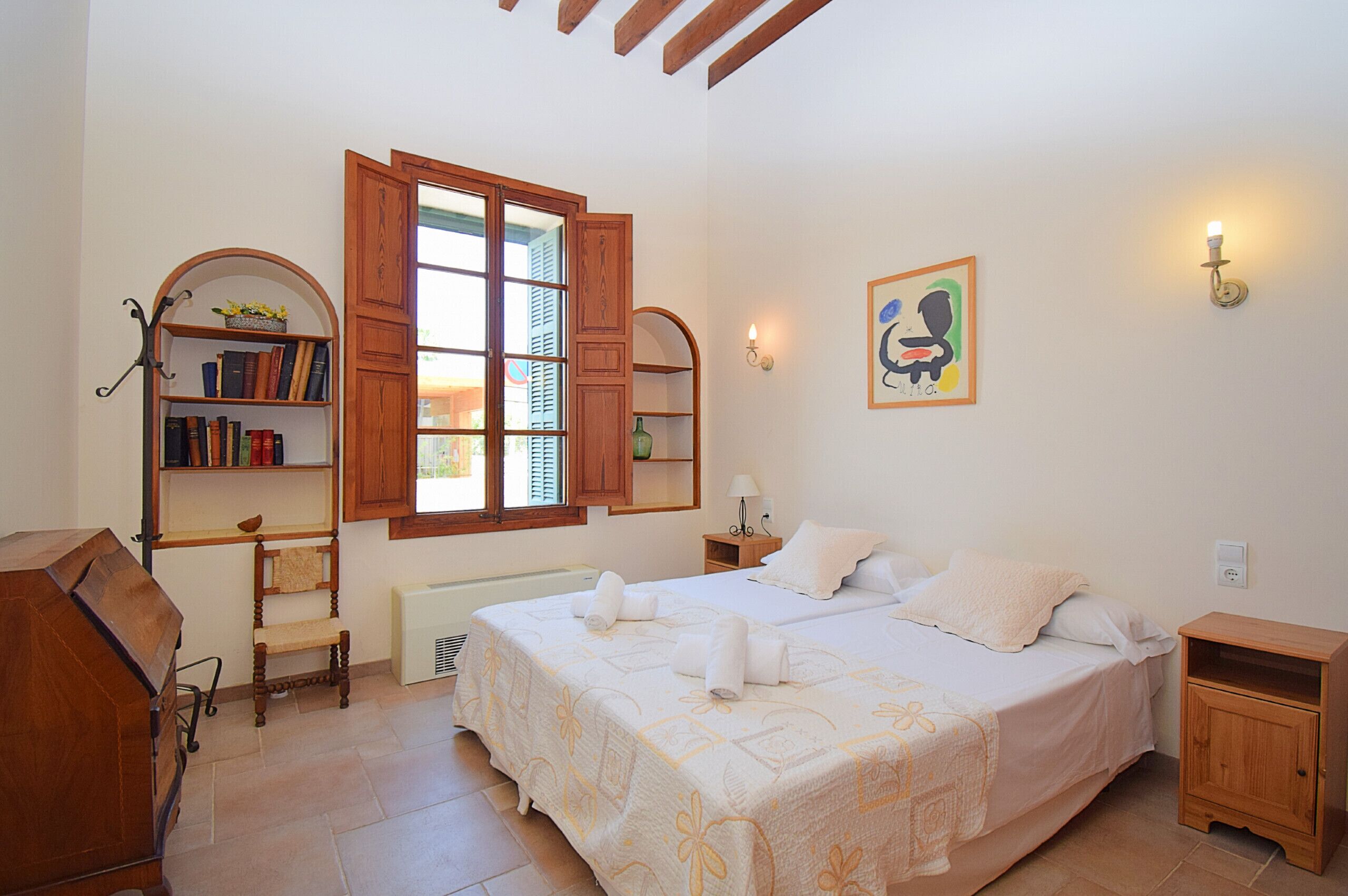 Ein Schlafzimmer mit einem Bett, einem Bücherregal, einem Schreibtisch und einem Fenster mit Fensterläden.
