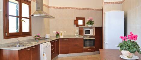 A kitchen with wooden cabinets, a stainless steel range hood, a built-in microwave, and a refrigerator.