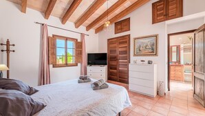 A bedroom with a bed, a TV, a dresser, a wardrobe, and a painting on the wall. - Son Coves Rural Cottage (Santanyi)