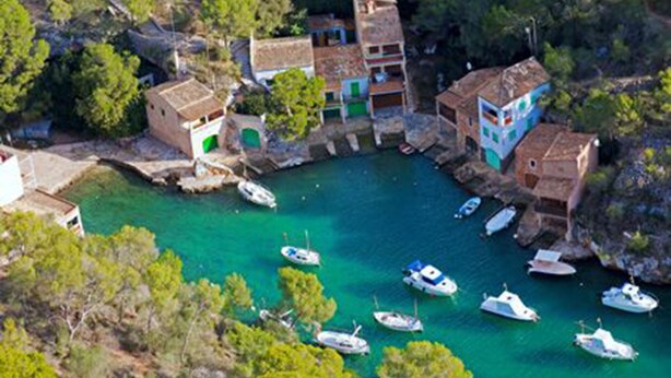 A coastal village with boats docked at a marina, surrounded by traditional buildings and lush greenery. - Son Coves Rural Cottage (Santanyi)
