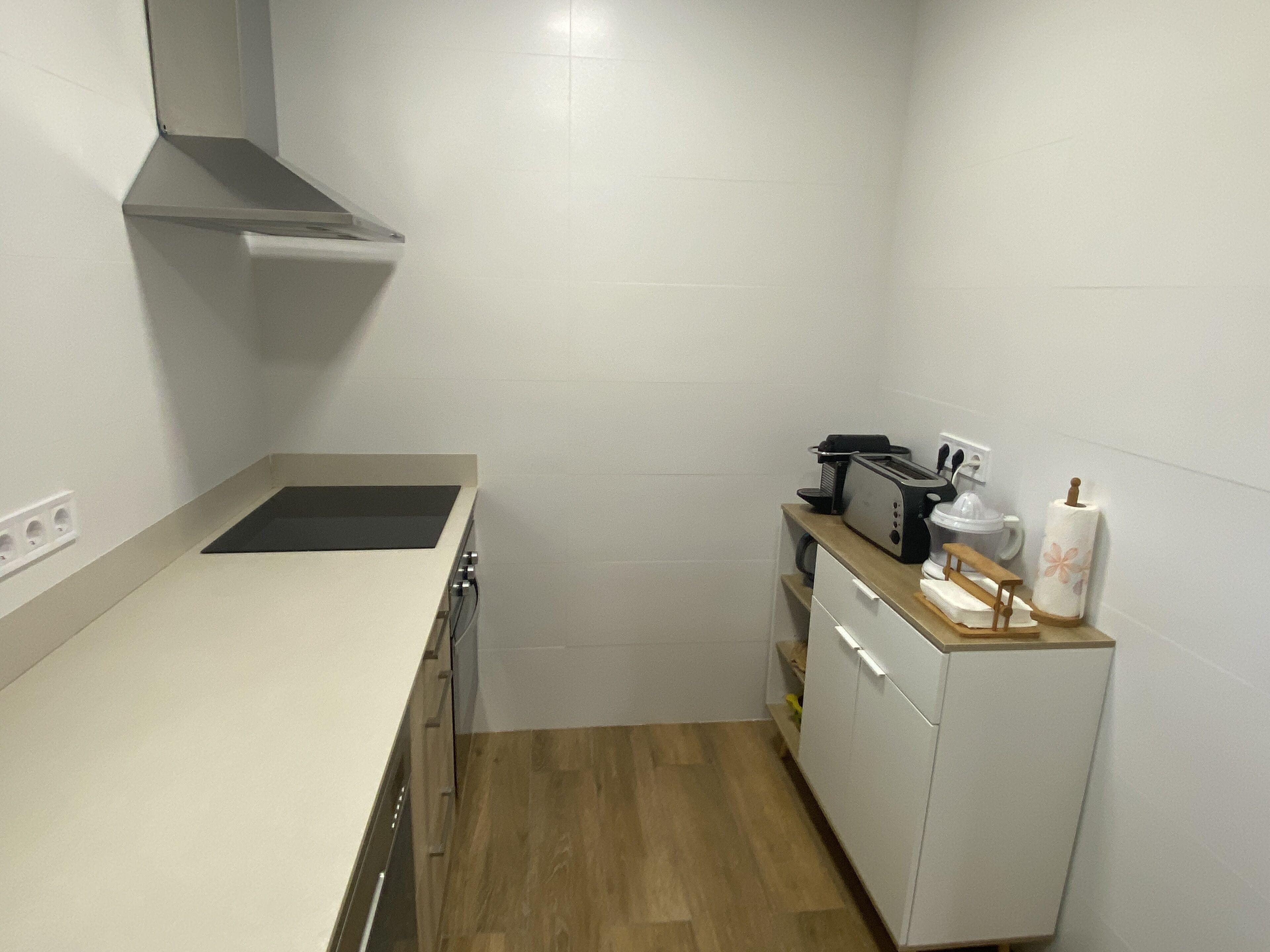 Eine kompakte Küche mit Herd, Toaster und kleinem Kühlschrank.