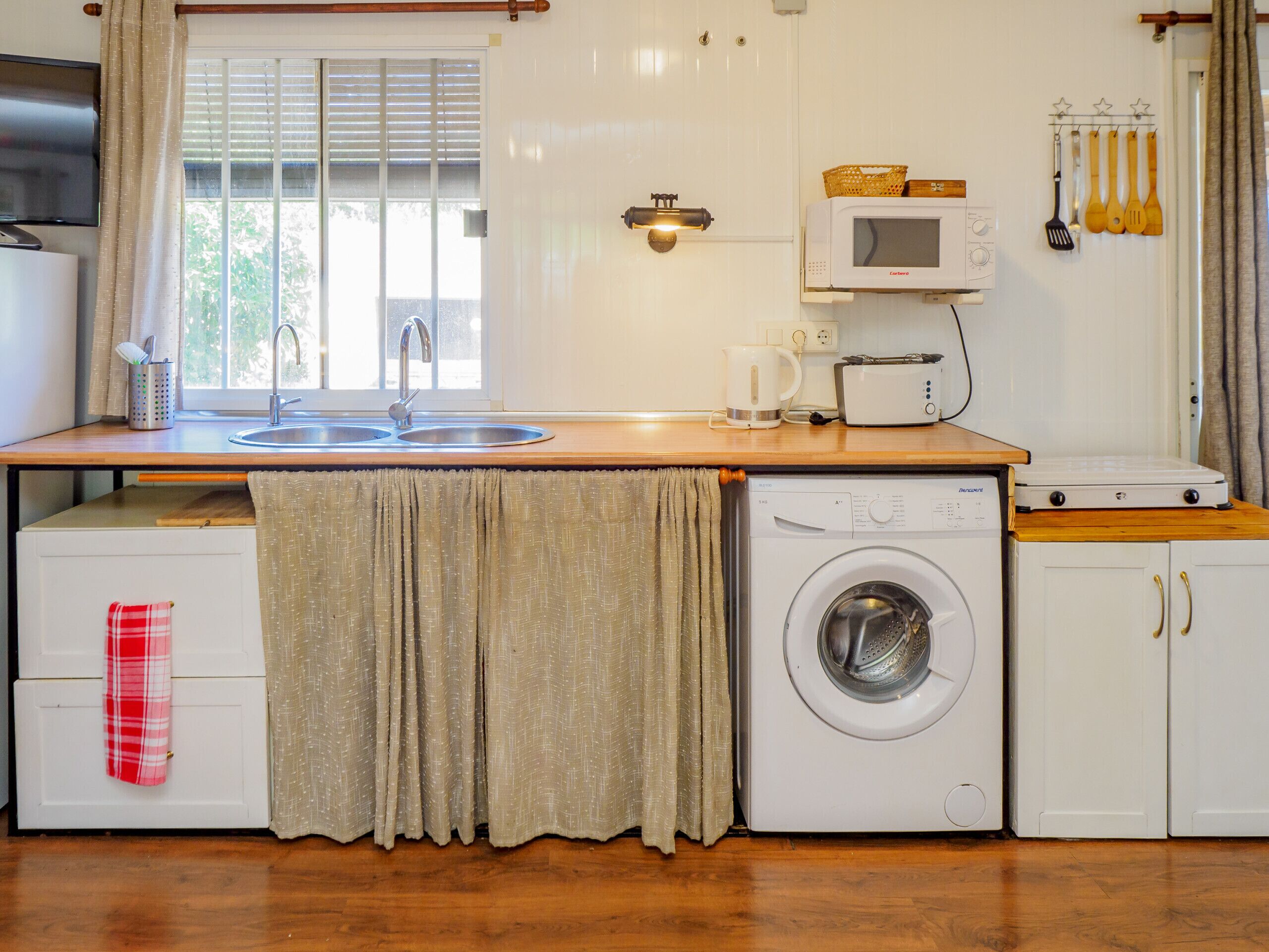 Una cocina funcional con lavadora, microondas y lavabo.