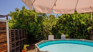Ein Freibad mit Holzterrasse und überdachtem Bereich mit Sonnenschirmen.