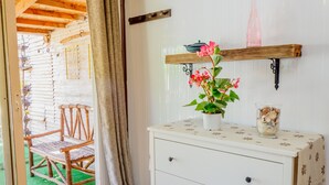Ein Zimmer mit Holzstuhls vor der Tür, einer weißen Kommode mit Schubladen, einem Blumentopf und einem Regal mit Dekoration.
