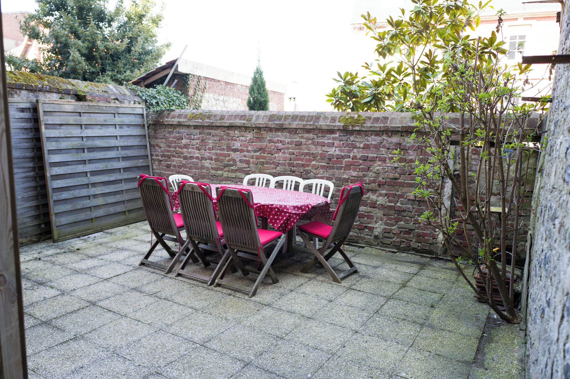 A patio with a table and chairs, a brick wall, and a wooden fence.