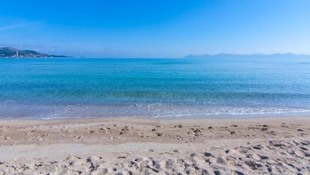 Una playa con aguas azul turquesa y una orilla arenosa.