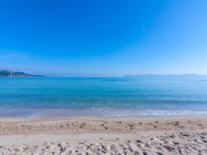 A beach with clear blue water and a sandy shore.