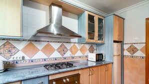 Une cuisine équipée d’une cuisinière à gaz, d’un four à micro-ondes et d’une hotte en acier inoxydable.