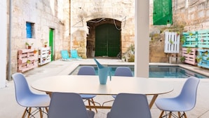 A courtyard with a pool, outdoor seating, and rustic stone walls.