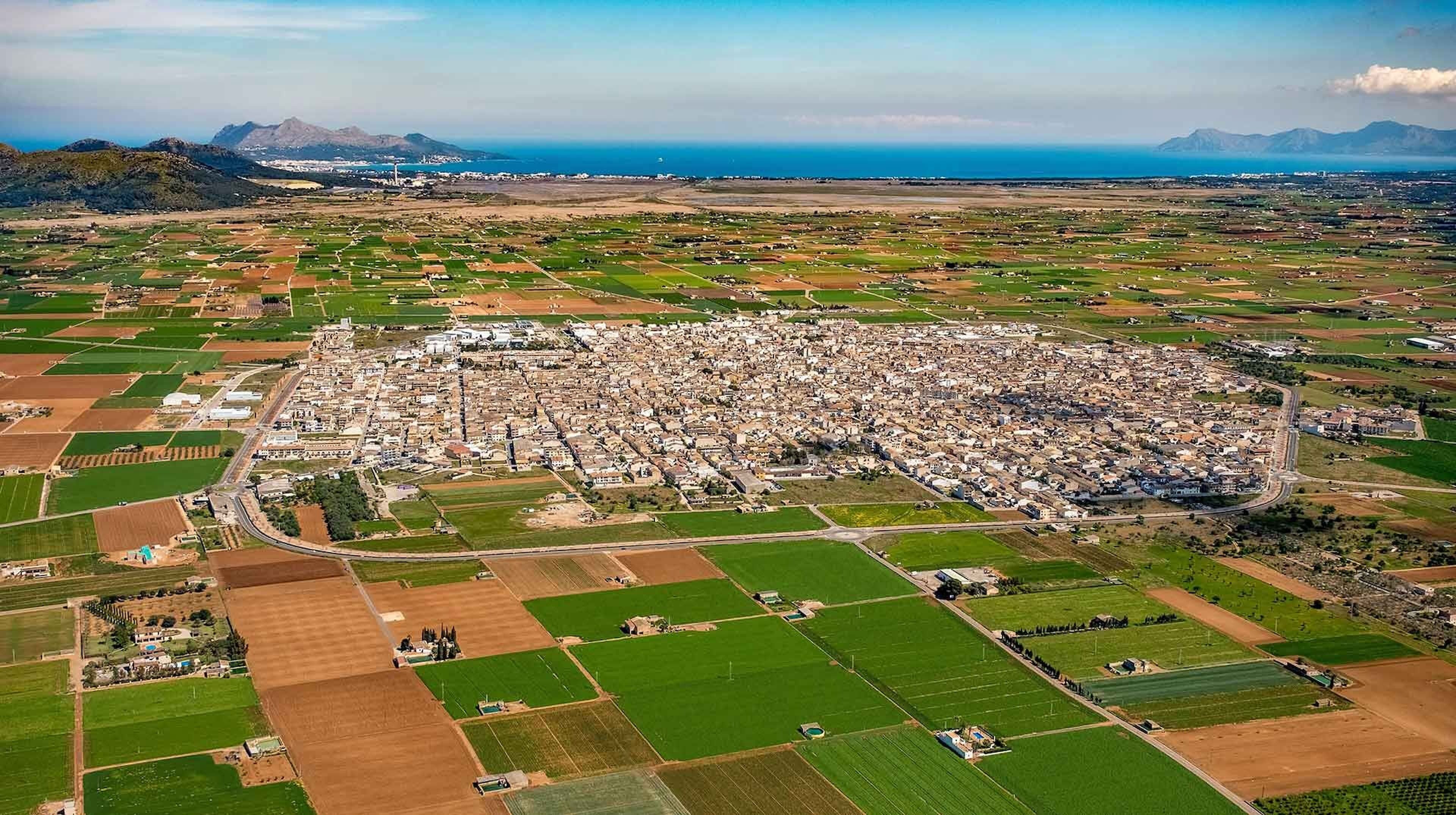 An aerial view of a town with a dense cluster of buildings surrounded by agricultural fields.