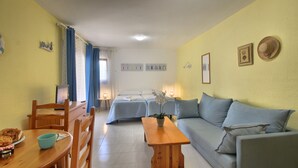 A cozy room with a wooden dining table, a sofa, and a bed with blue bedding.