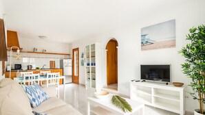 Een moderne woonkamer met een bank, salontafel, tv-meubel en een eethoek met stoelen en een tafel.