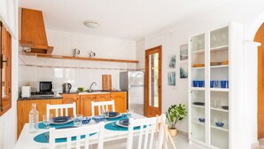 Een moderne keuken met witte kastjes, een houten aanrecht en een eethoek met een witte tafel gedekt voor vier personen.