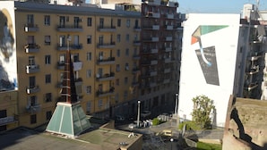 En bygning med flere etager, altaner, et centralt torv og en moderne bygning med geometrisk design.