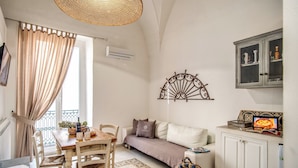 Un salon chaleureux avec une table à manger en bois, un canapé blanc et un élément décoratif en métal accroché au mur.
