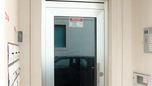 A hotel entrance with a glass door, a sign above the door, and a tiled floor.