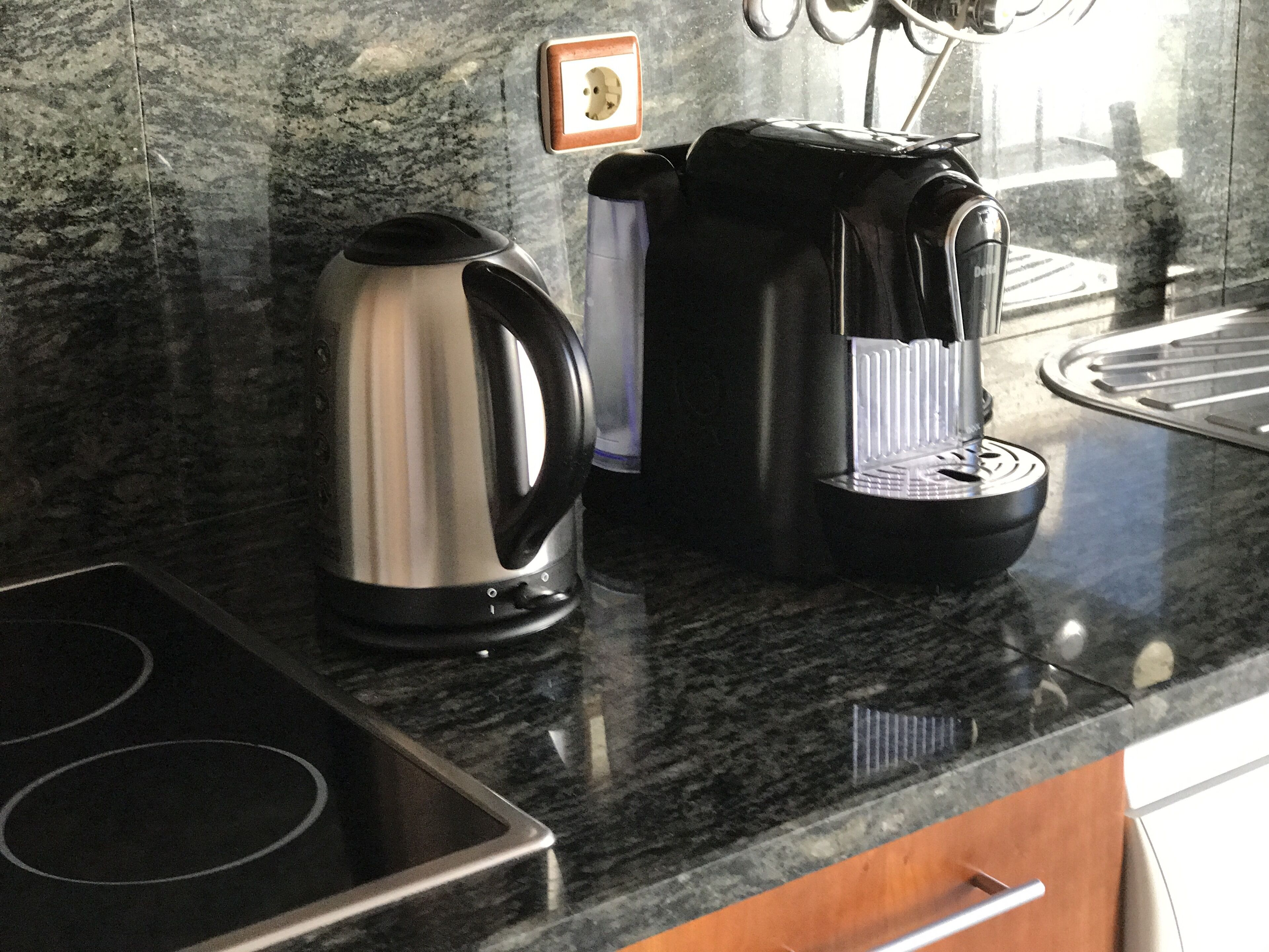 A kitchen with a stainless steel kettle, a coffee maker, and a built-in stovetop.